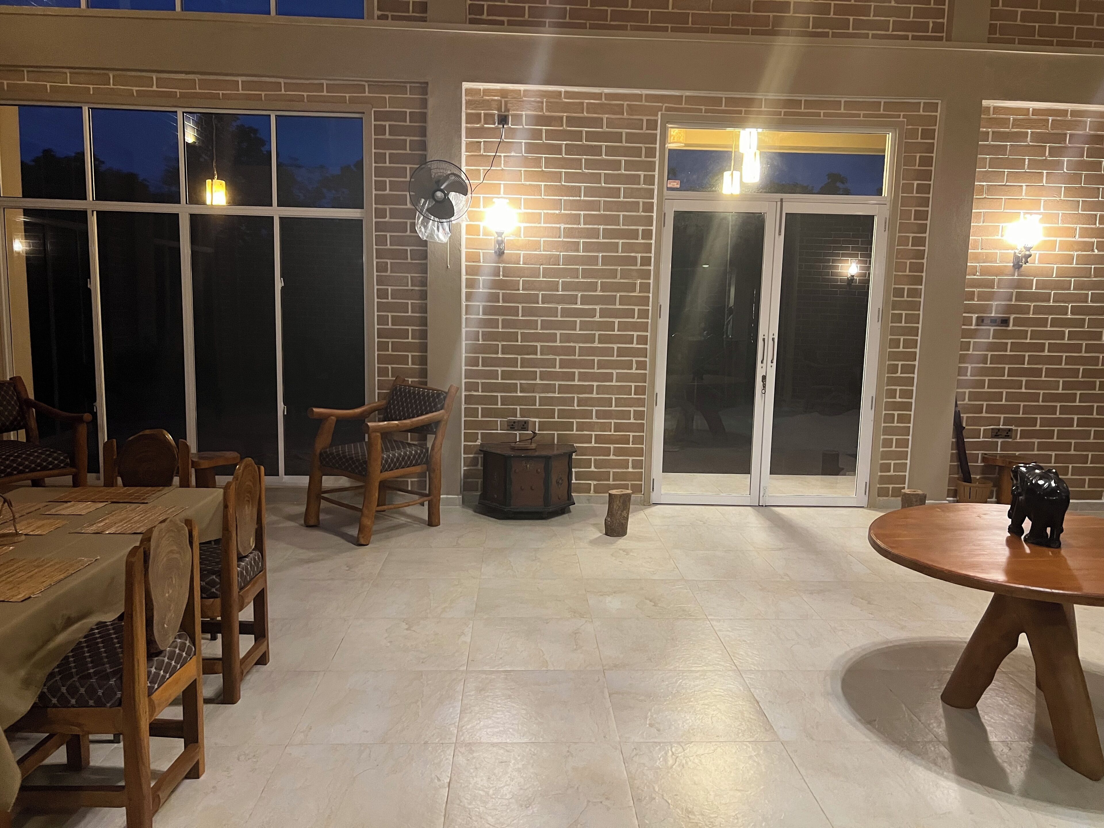 An outdoor patio with brick walls, a wooden table, and chairs.