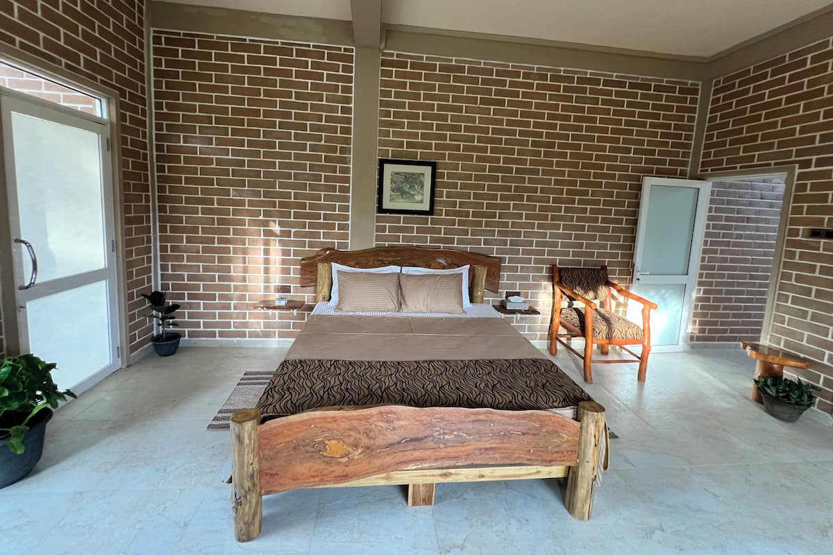 Un dormitorio espacioso con una cama grande, un banco de madera, una silla y una planta en maceta.