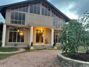 A modern two-story house with large windows, a visible staircase, and a well-maintained garden.