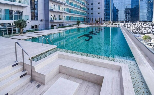Un hotel moderno con una amplia piscina cubierta, un jardín bien cuidado y vistas a la silueta urbana.