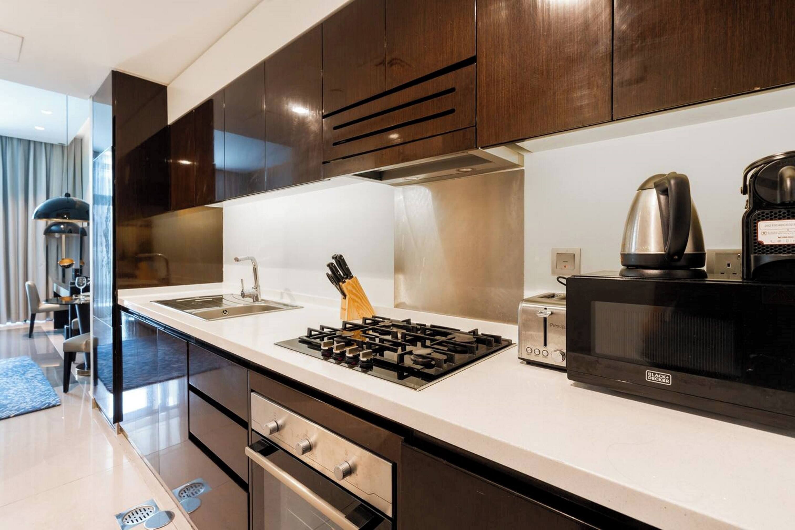 Una cucina moderna con piano cottura a gas, forno a microonde, bollitore e lavello.