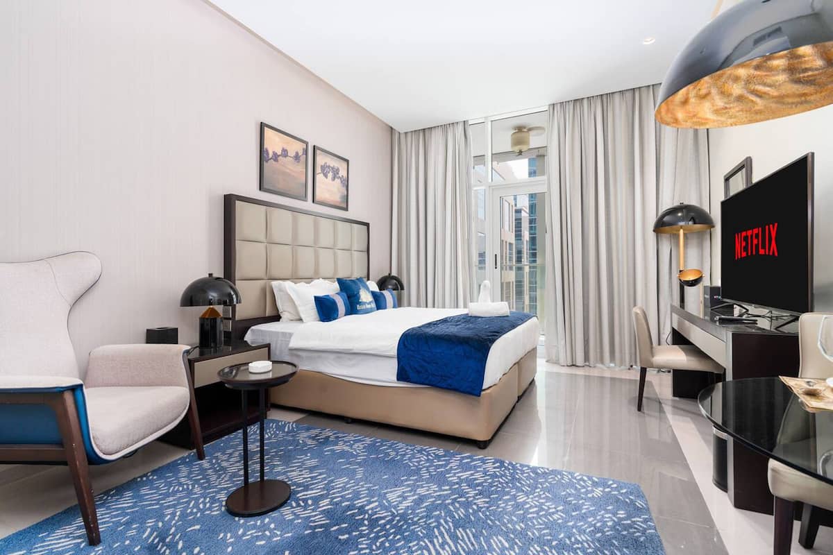 Una habitación de hotel moderna con una cama grande, un escritorio, un televisor y vistas a la ciudad.