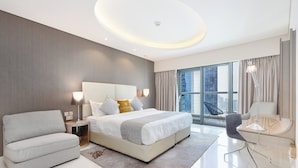 A modern hotel room with a large bed, a sofa, a desk, and a view of the city through large windows. - GLOBALSTAY. DAMAC Majestine Apartments (Dubai)