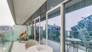 A balcony with glass railings, a white table, and two chairs. - GLOBALSTAY. DAMAC Majestine Apartments (Dubai)