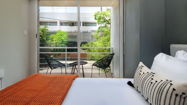 Ein Hotelzimmer mit Bett, großem Fenster und Balkon mit Stühlen und Tisch.