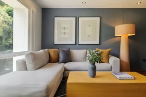 Ein modernes Wohnzimmer mit einer Couch, einem Couchtisch und einer Lampe. Zwei gerahmte Kunstwerke hängen an der Wand.
