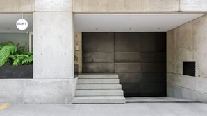 A concrete staircase leading to a dark door, with a hanging sign that reads "DLAMT" and a potted plant to the left. - Stylish 2-Bdr Haven with Relaxing Balcony (Ciudad de México)