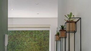 A modern interior with a dining area, a balcony with a green view, and a wall-mounted plant shelf. - Stylish 2-Bdr Haven with Relaxing Balcony (Ciudad de México)