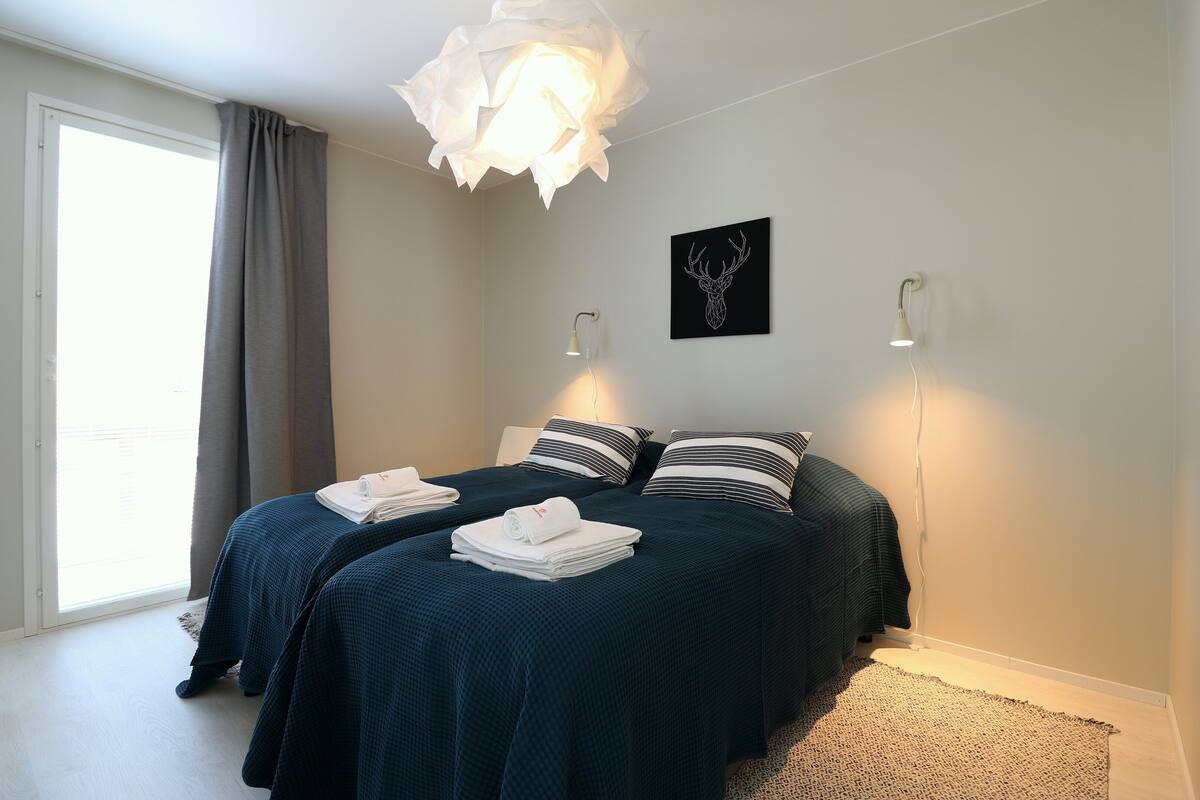 Una camera da letto con due letti, una grande finestra e un lampadario a parete.