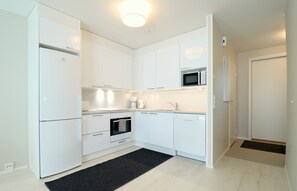 A modern kitchen with white cabinets, a built-in oven, a microwave, and a coffee maker. - Forenom Serviced Apts Espoo Perusmäki 4 (Espoo)