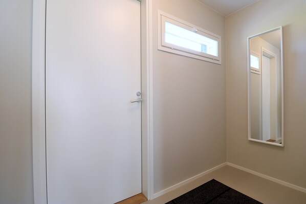 A hallway with a closed door, a small window, and a mirror on the wall. - Forenom Serviced Apts Espoo Perusmäki 4 (Espoo)