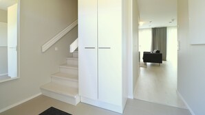 Eine Treppe führt zu einer Zwischenebene mit einem weißen Kleiderschrank und einem schwarzen Sofa im Hintergrund.
