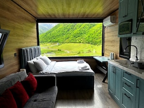 A bedroom with a large window, a bed, a sofa, and a small table with a kettle. - Runaway House - Qalaciq (Ismailli)