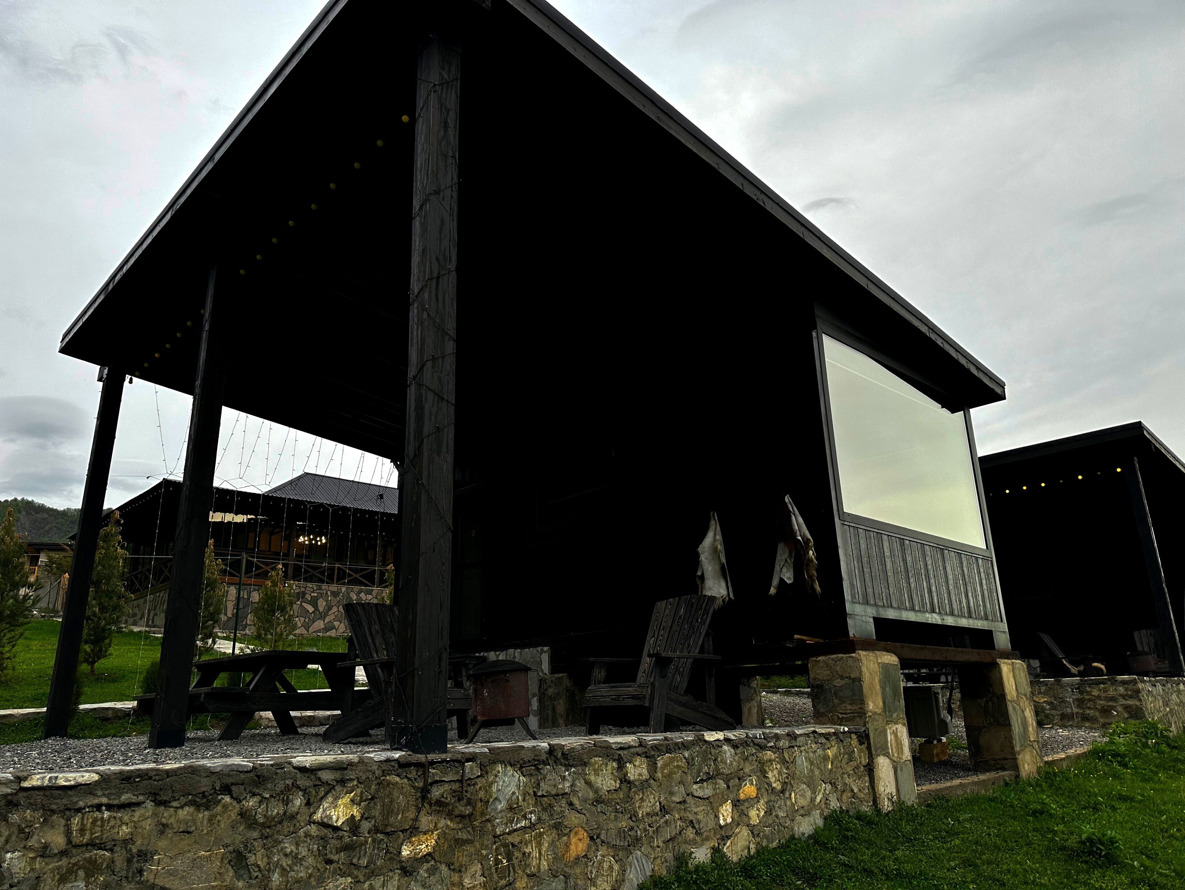 Une cabane rustique avec des fondations en pierre, un toit en pente et une grande fenêtre.