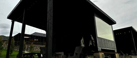 Une cabane rustique avec des fondations en pierre, un toit en pente et une grande fenêtre.