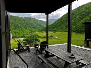 Un espace extérieur abrité, aménagé avec des sièges, et offrant une vue sur une vallée et des montagnes.