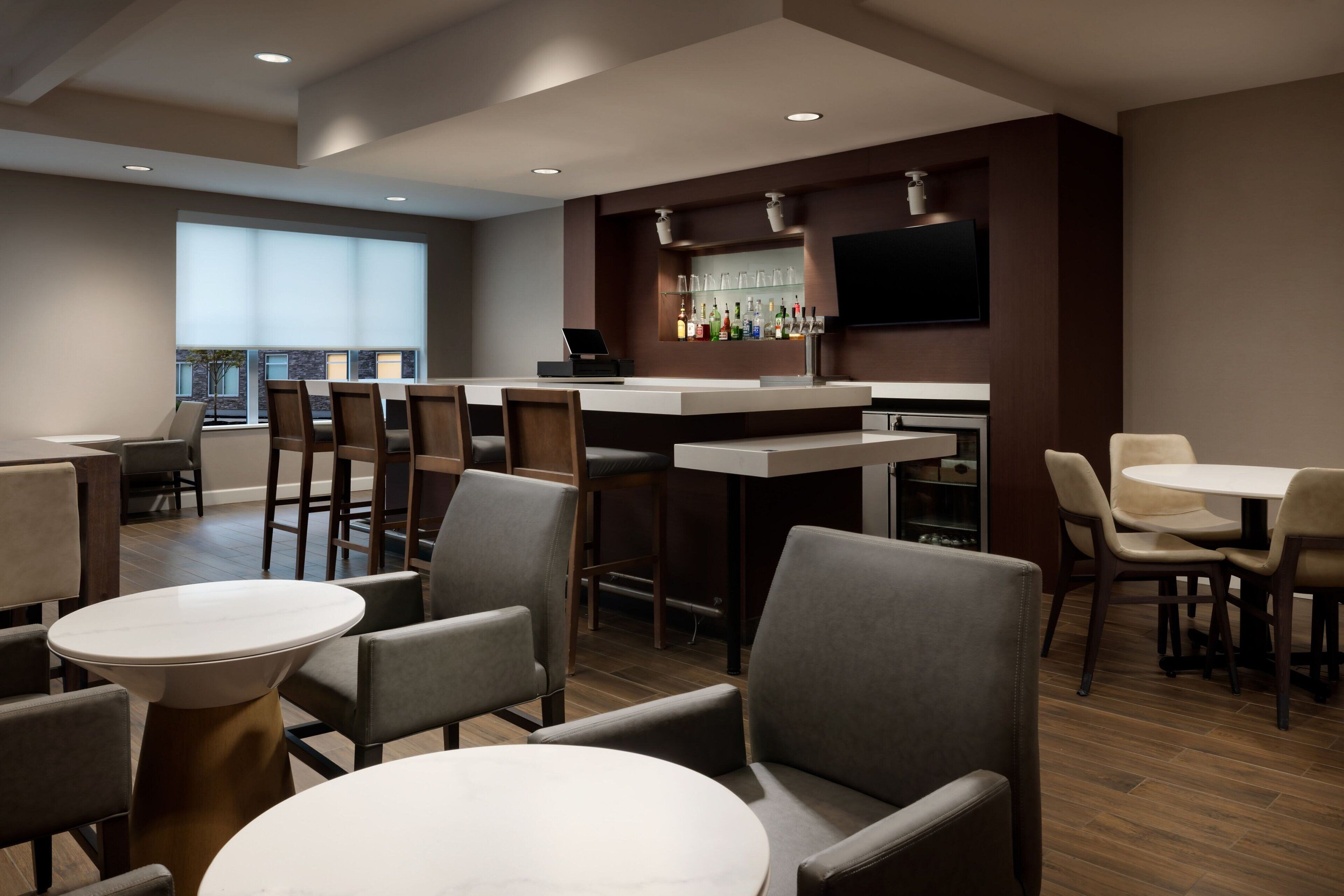 A modern bar area with a counter, seating, and a large window.