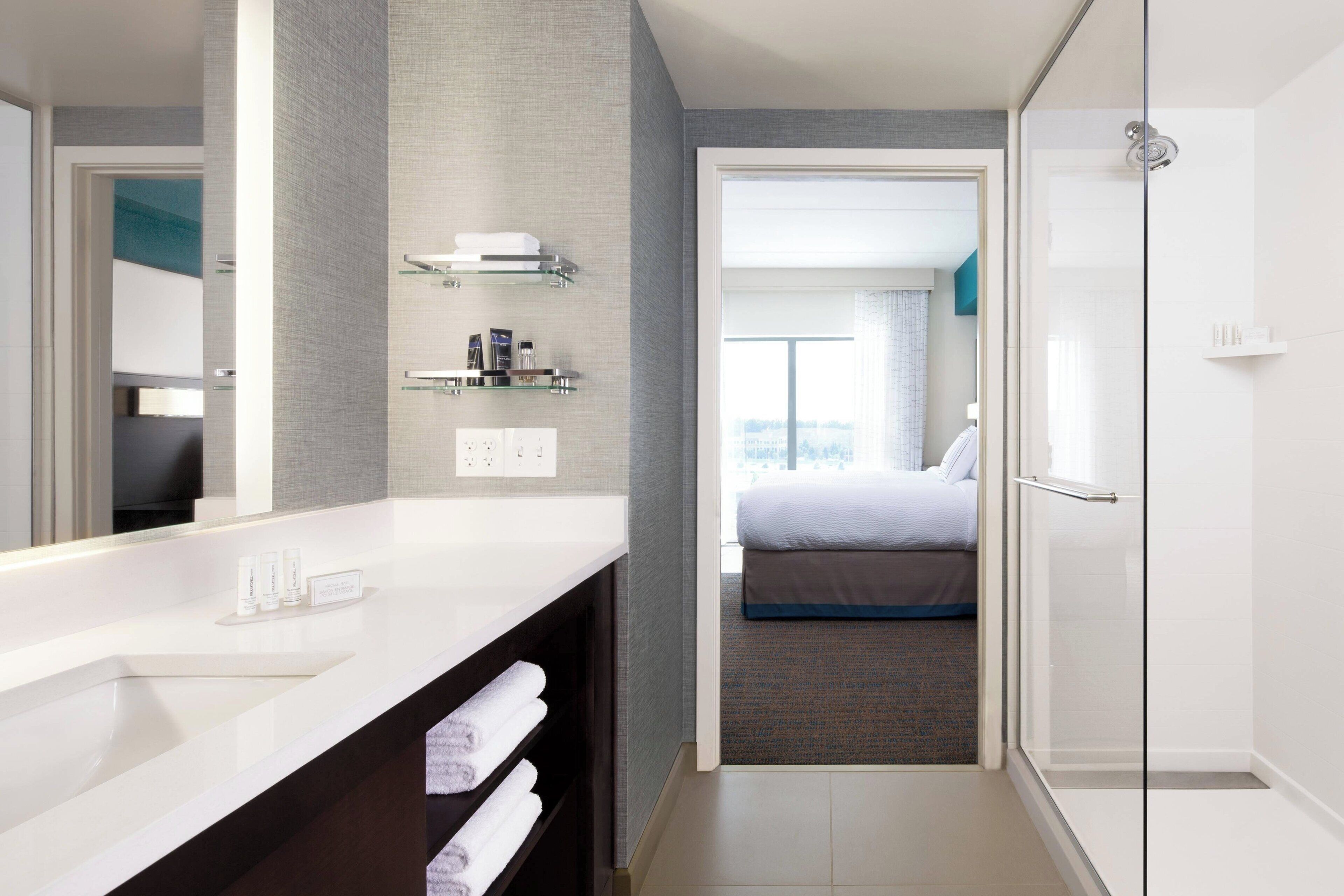 A modern bathroom with a large mirror, a white sink, and a glass shower enclosure.
