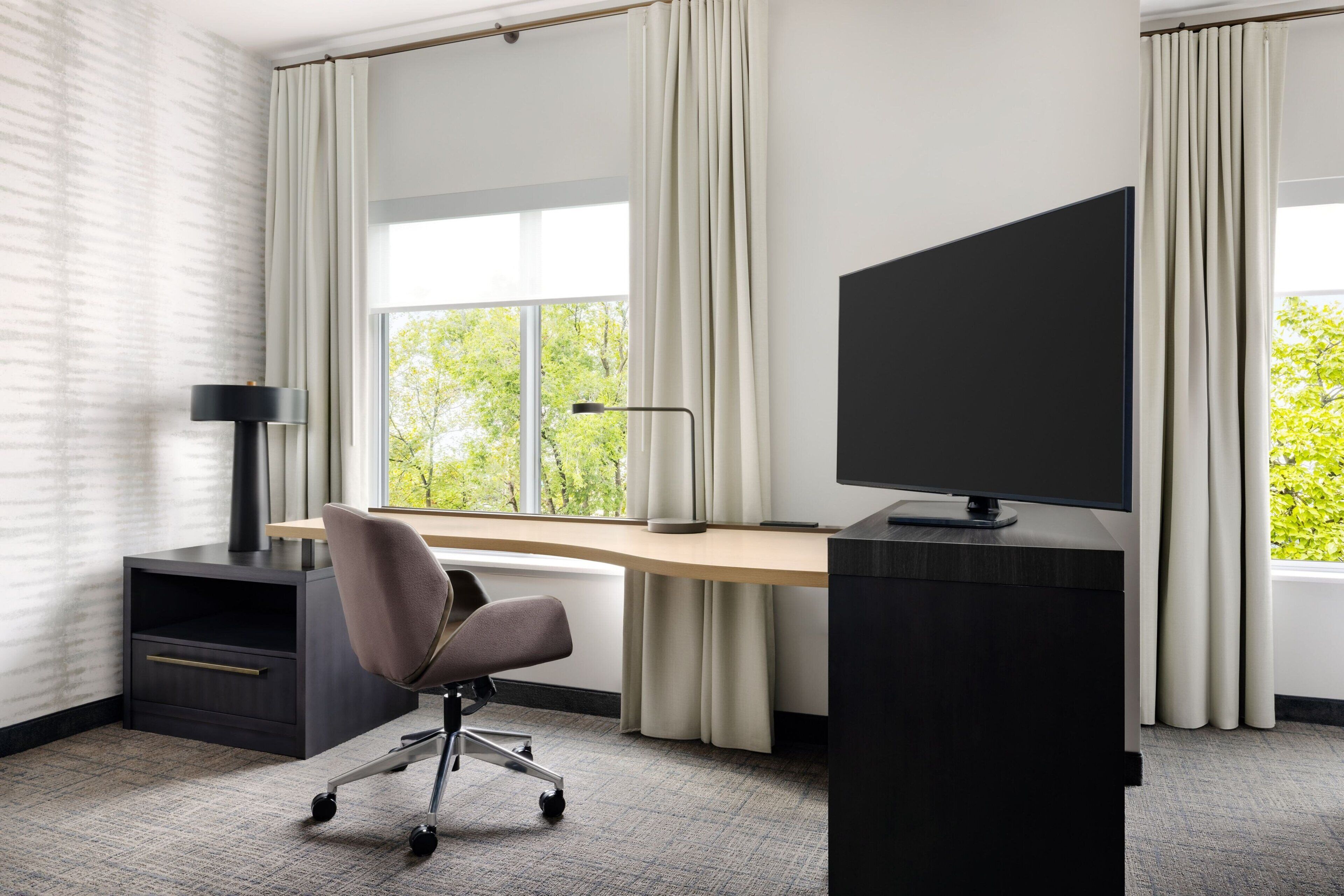 A modern office space with a desk, chair, and large window.