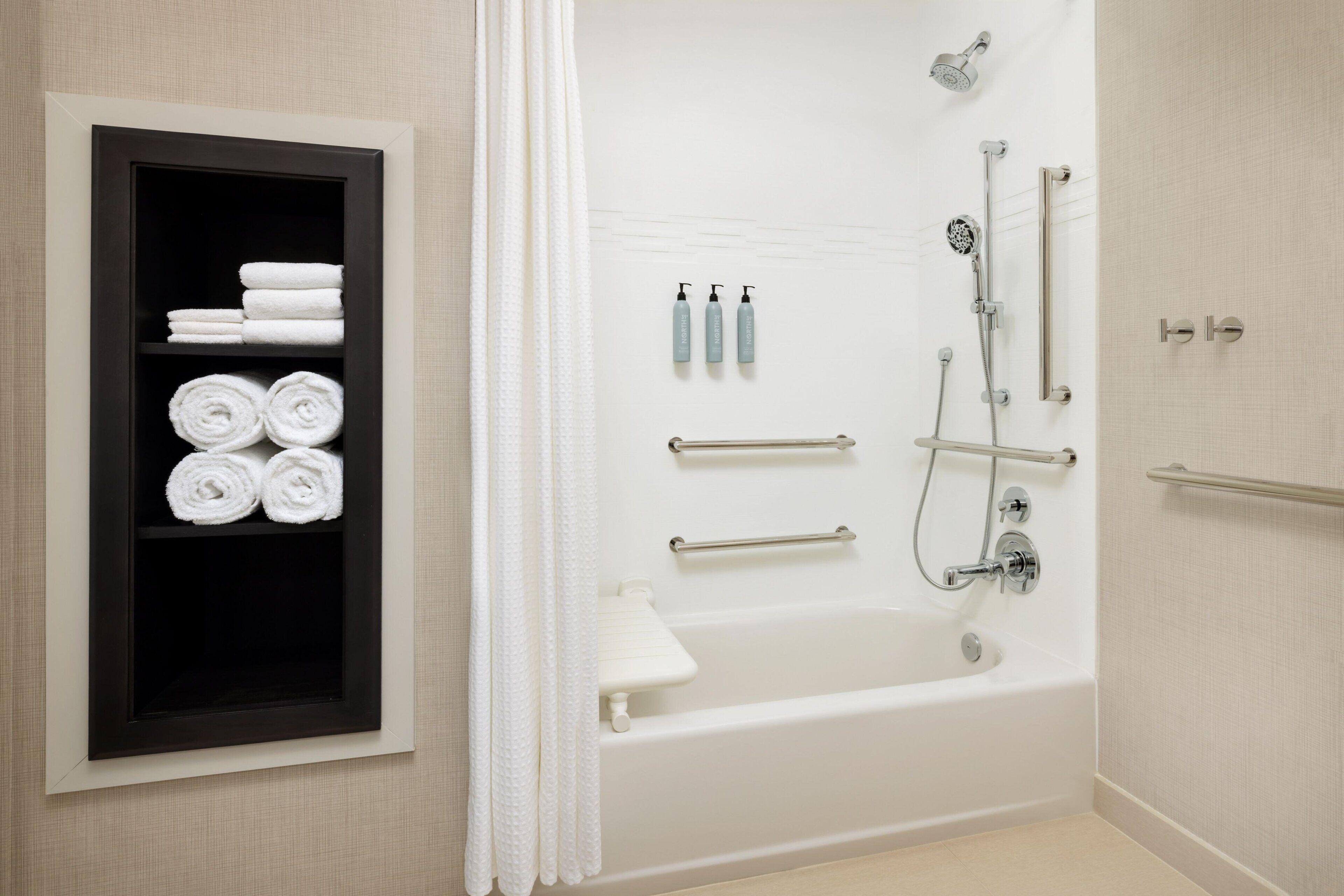 A modern bathroom with a bathtub, shower, and towel rack.