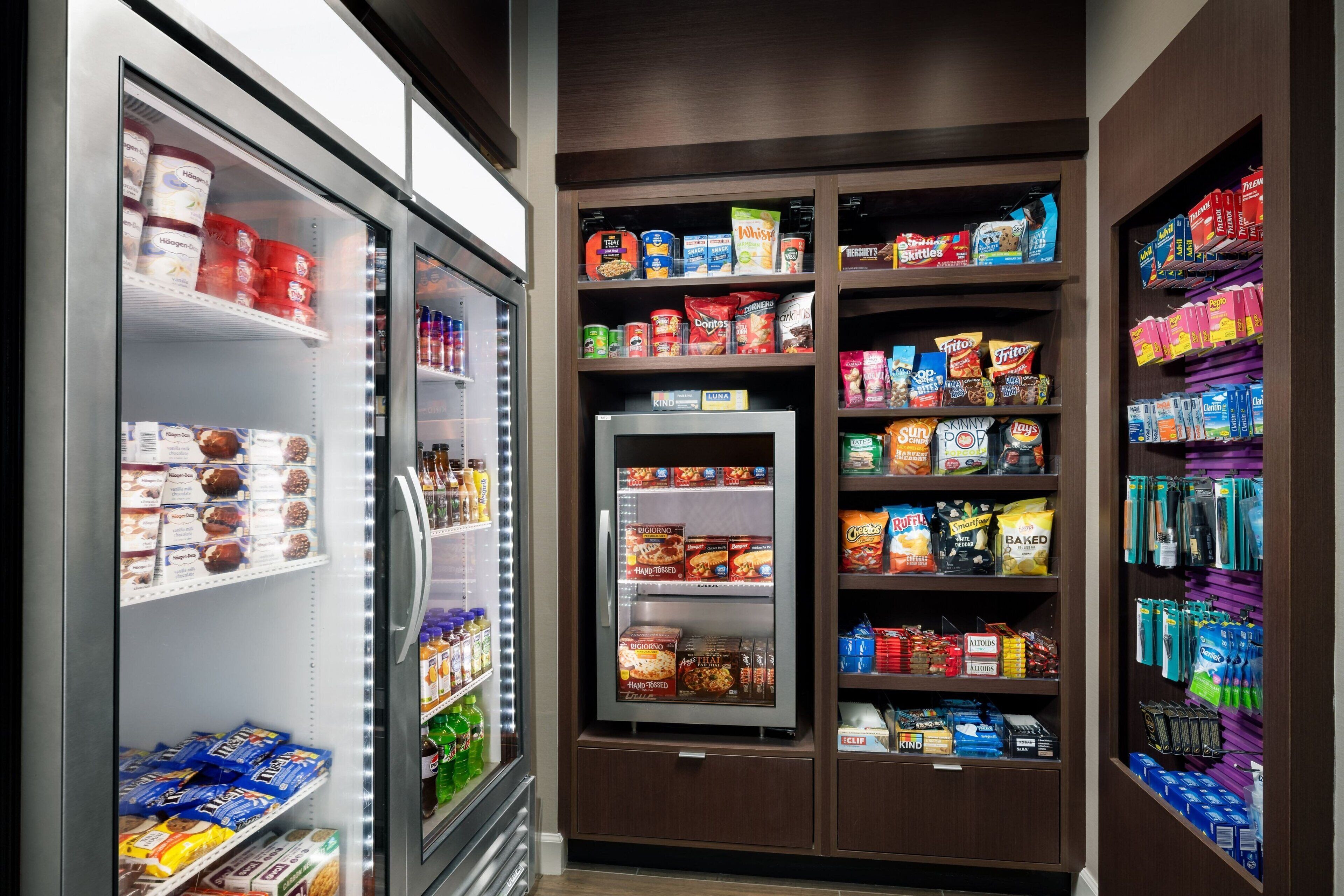 Un refrigerador exhibe diversos alimentos y una estantería llena de aperitivos y bebidas.