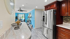 A kitchen with a marble countertop, stainless steel refrigerator, wooden cabinets, and a ceiling fan. - Quiet Comfy Getaway 3 BDR home. Close to Bradley Airport. (Windsor)