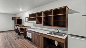 A modern kitchen with wooden cabinets, a white countertop, and a built-in dishwasher. - WoodSpring Suites Beaverton - Portland West (Beaverton)