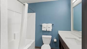 Ein Badezimmer mit einer weißen Badewanne, einer weißen Toilette und einem weißen Waschbecken mit Spiegel.