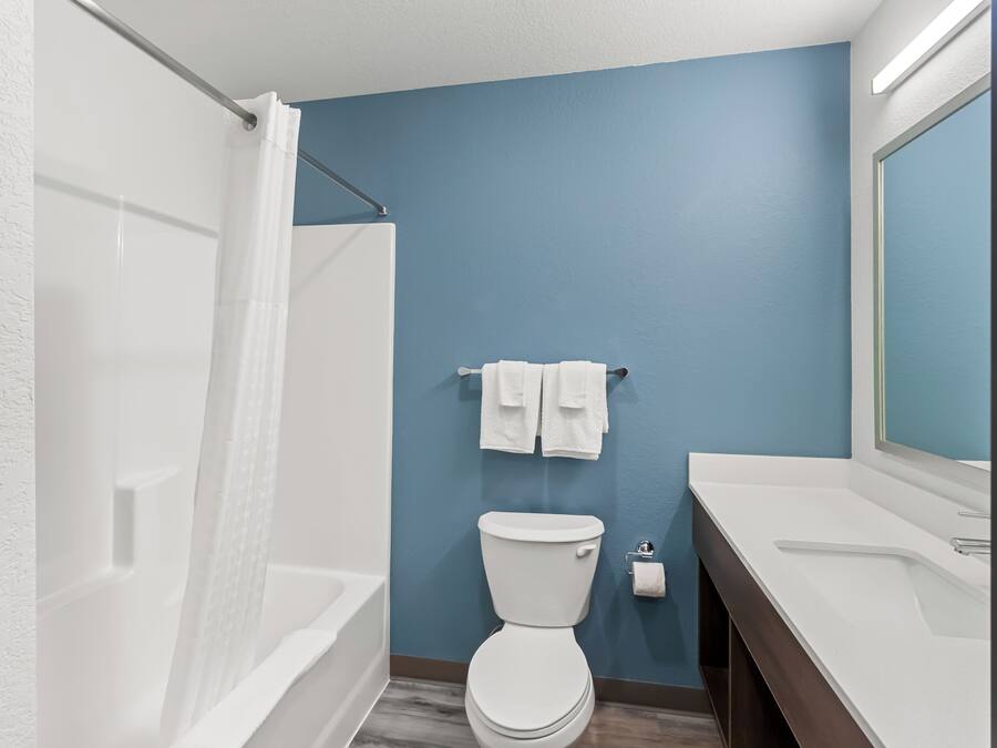 Ein Badezimmer mit einer weißen Badewanne, einer weißen Toilette und einem weißen Waschbecken mit Spiegel.