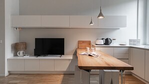 Une cuisine moderne avec une table à manger en bois, un téléviseur à écran plat noir et une machine à café.