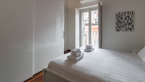 A hotel room with a bed, a window with a view of buildings, and a wall art piece. - Italianway - Fabbri 12 D (Milan)
