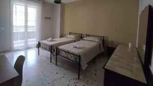 Habitación de hotel con dos camas, un escritorio, una silla y un ventanal con vistas.