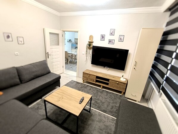 A living room with a sofa, a coffee table, a TV, and a cabinet. - Masha Suite  (Karaman)
