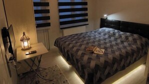 A bedroom with a bed, a desk, a chair, a lamp, and a ceiling fan. - Masha Suite  (Karaman)