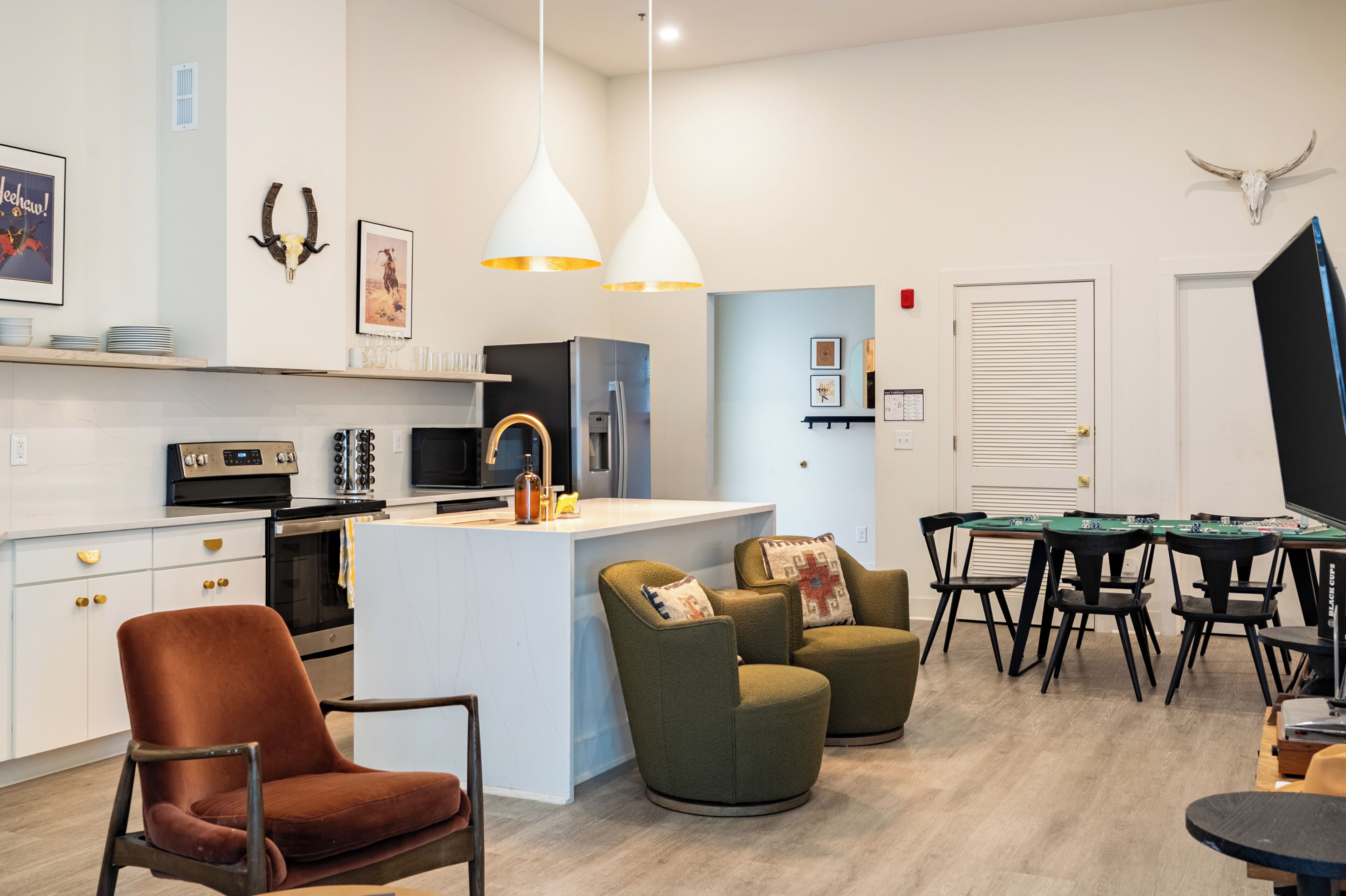 Una cocina moderna con armarios blancos, una isla central e iluminación colgante.