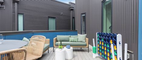 A deck with wicker furniture, a round table, and a ping pong table.