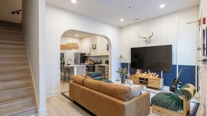 Una sala de estar moderna con un sofá, una mesa de centro, un televisor y una guitarra.