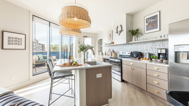 Una cocina moderna con una isla central, electrodomésticos de acero inoxidable y un amplio ventanal con vistas a la ciudad.