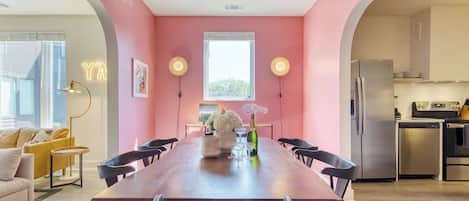A dining area with a wooden table, chairs, and a vase of flowers.