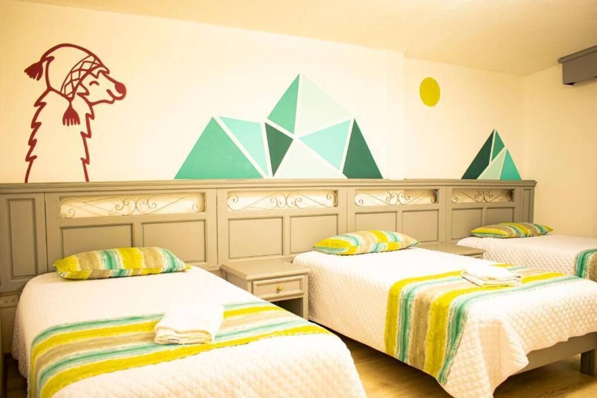 Een hotelkamer met twee bedden, elk voorzien van gestreept beddengoed en een nachtkastje. Een muurschildering toont een hond en geometrische vormen.