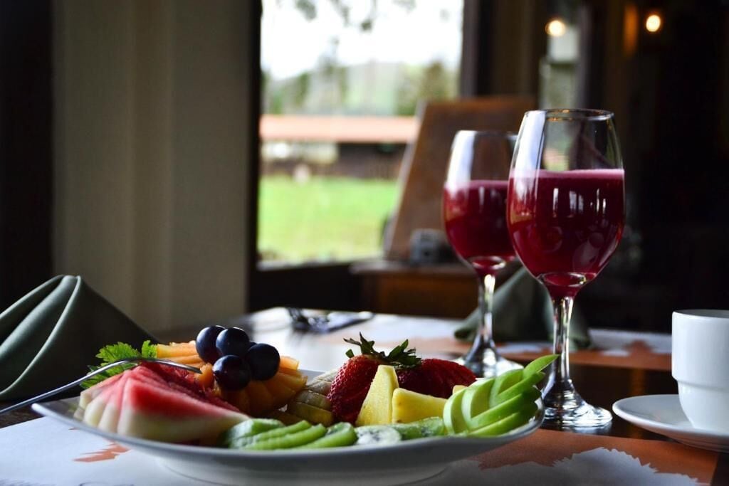 Een ontbijtsetting met een bord vers fruit en twee glazen rode sap.