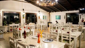 Un restaurant avec des tables et des chaises blanches, un plafond en bois et un lustre.