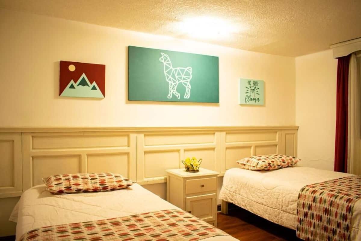Een hotelkamer met twee bedden, een nachtkastje en decoratieve wandkunst.