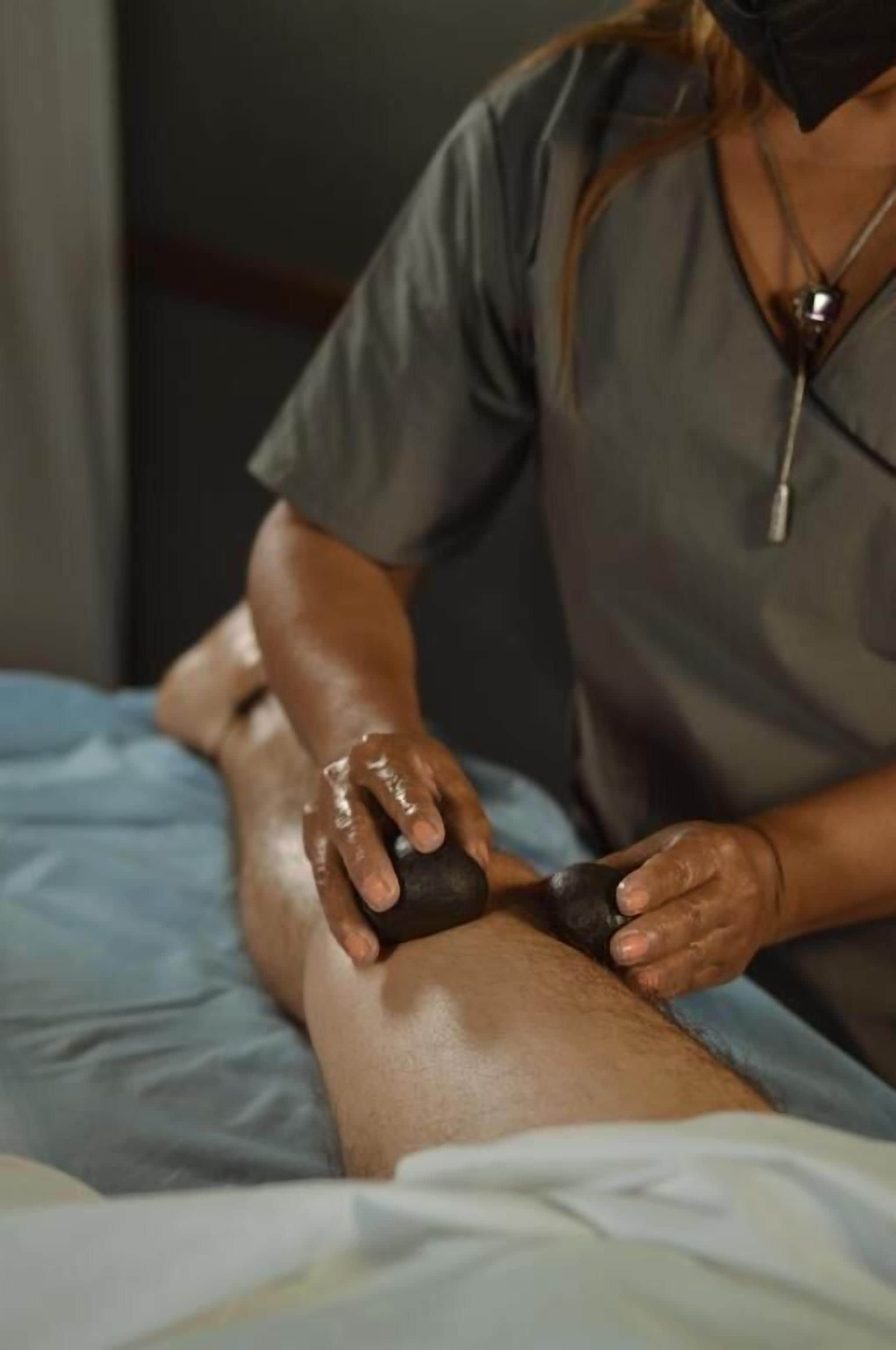 A person applying a treatment to another person's leg on a bed.