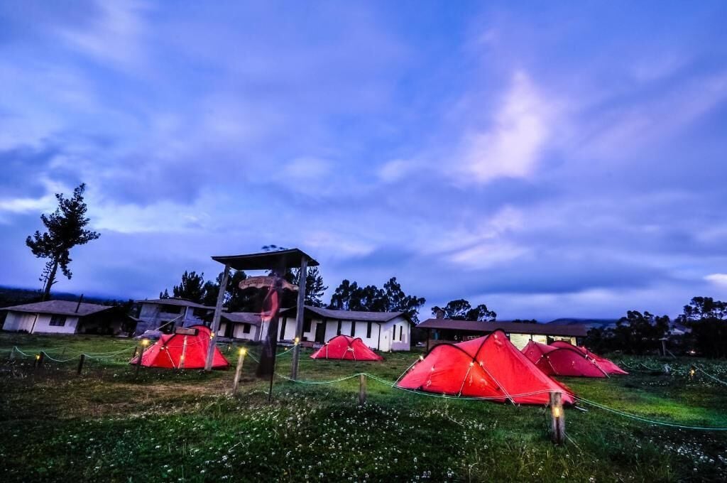 A campsite with red tents and a wooden structure in the center.
