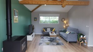 Ein modernes Wohnzimmer mit Kamin, grauen Sofas, einem Couchtisch und einem großen Fenster.