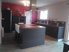 A modern kitchen with a central island, dark cabinetry, and a red accent wall.