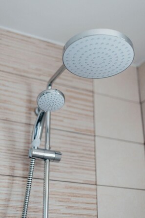 A showerhead with a round, perforated design, attached to a chrome fixture.
