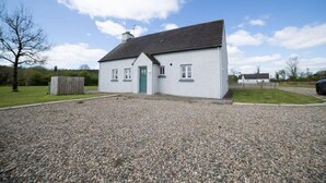 A single-story white house with a dark roof, a green door, and a gravel driveway. - Cottage, 3 Bed,sleeps 7, Free Parking (Enniskillen)