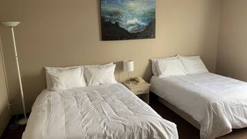 A hotel room with two beds, a nightstand with a lamp, and a painting on the wall.
